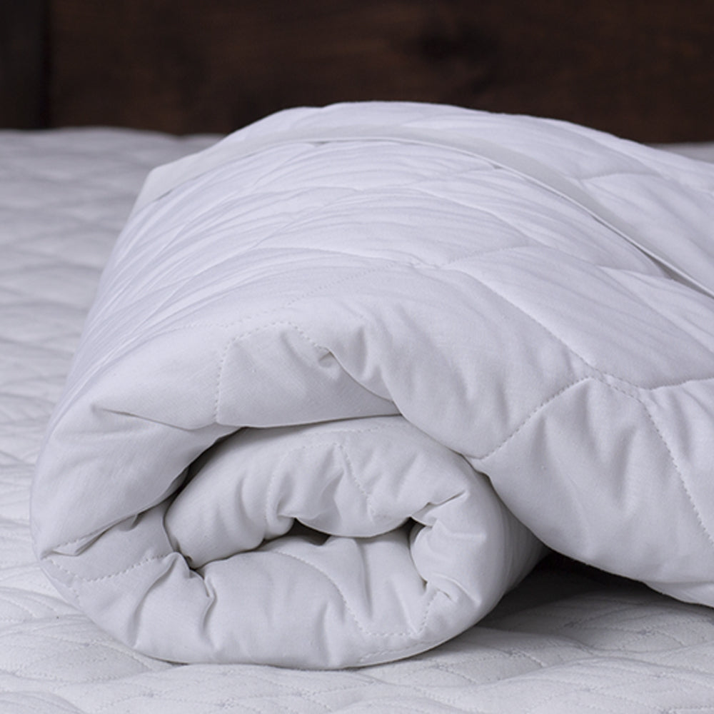 Rolled-up white quilted mattress protector on a mattress
